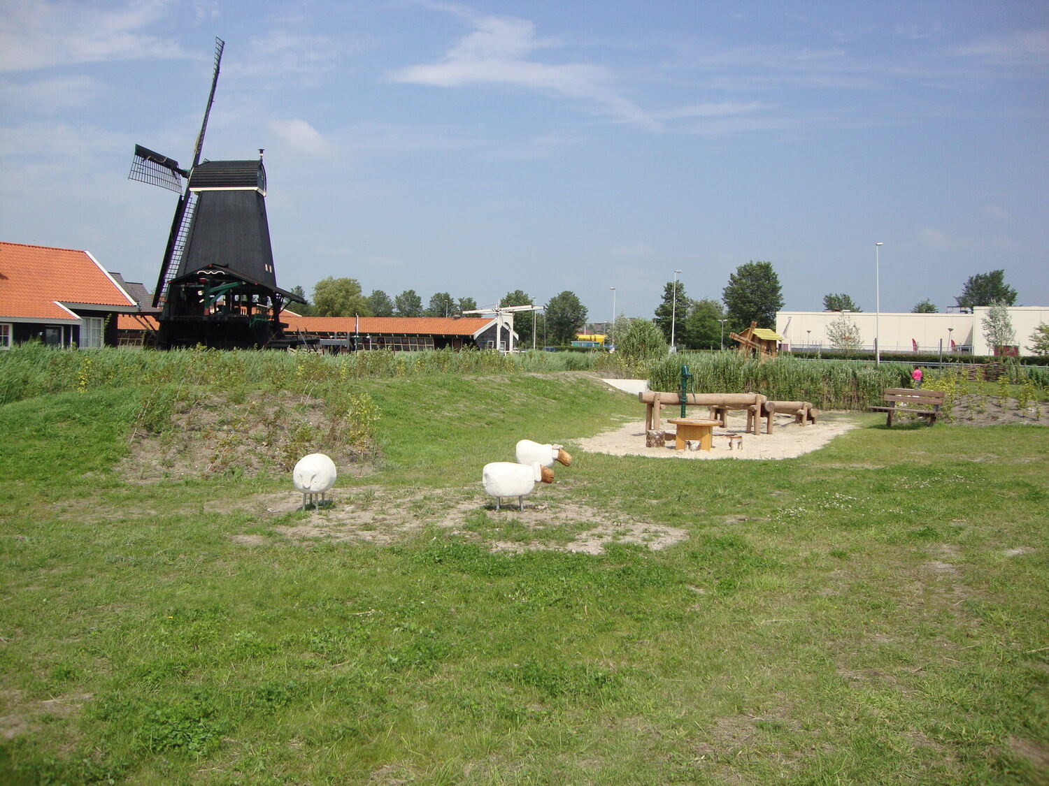 Natuurlijke speeltuin met boomstammen en een molen op de achtergrond