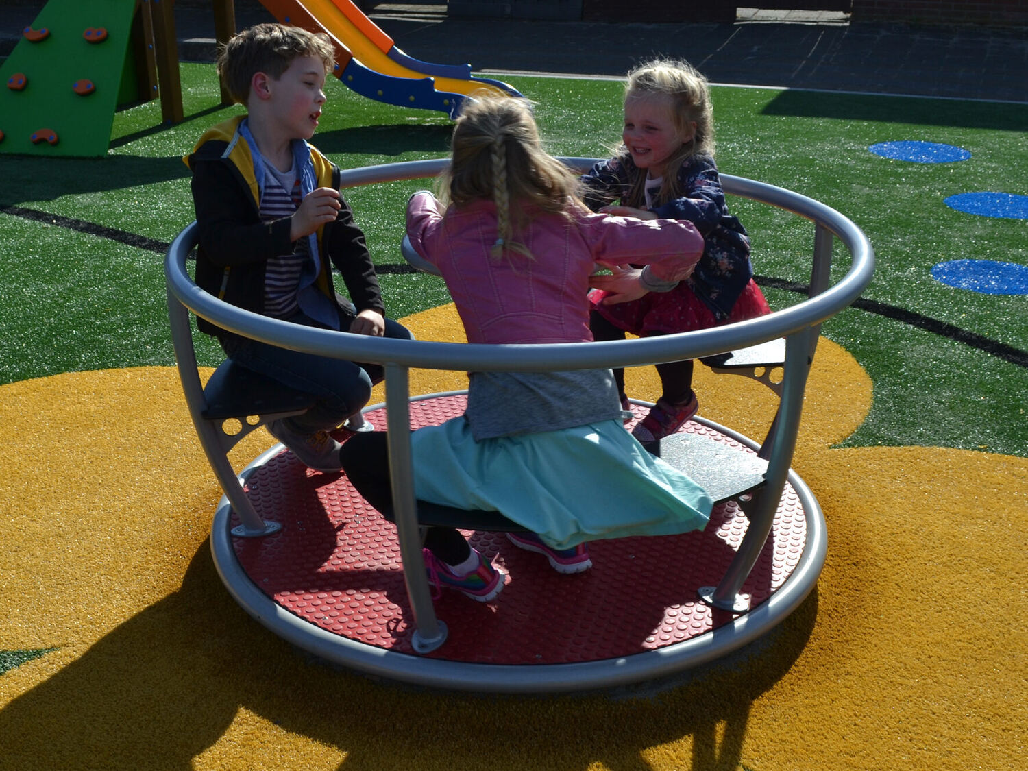 Kinderen op een draaimolen op een speelplaats met valondergrond