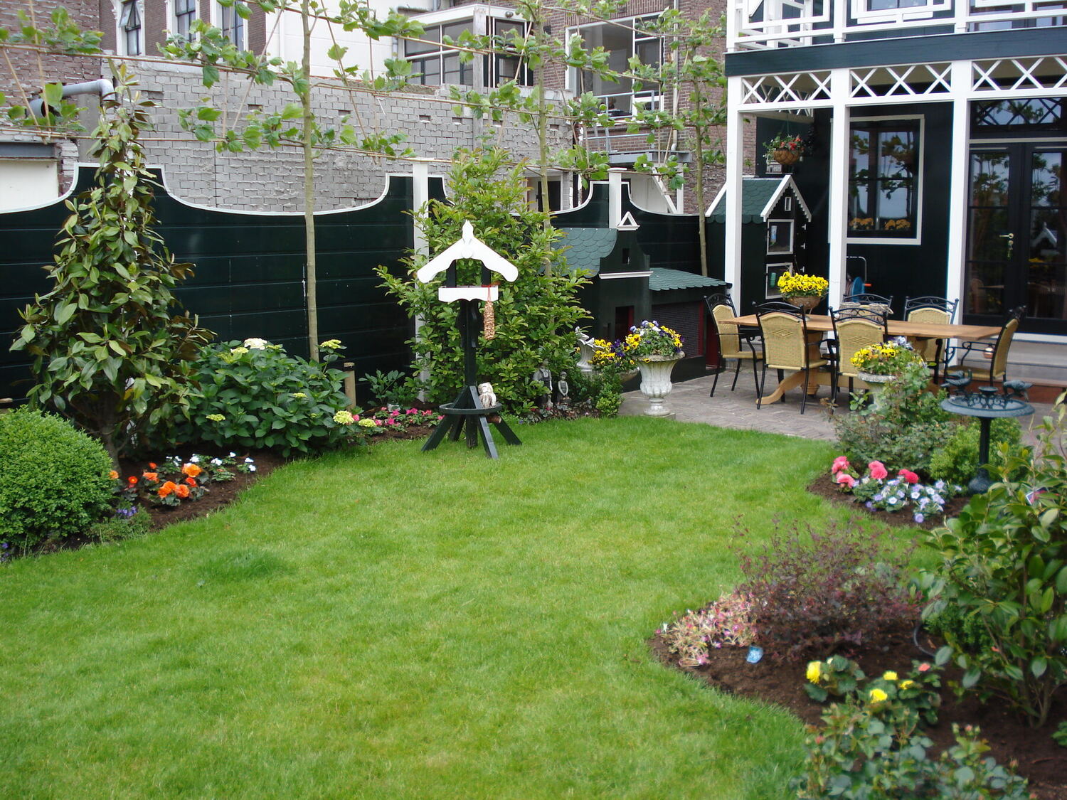 Tuin met gazon, borders en vogelhuis