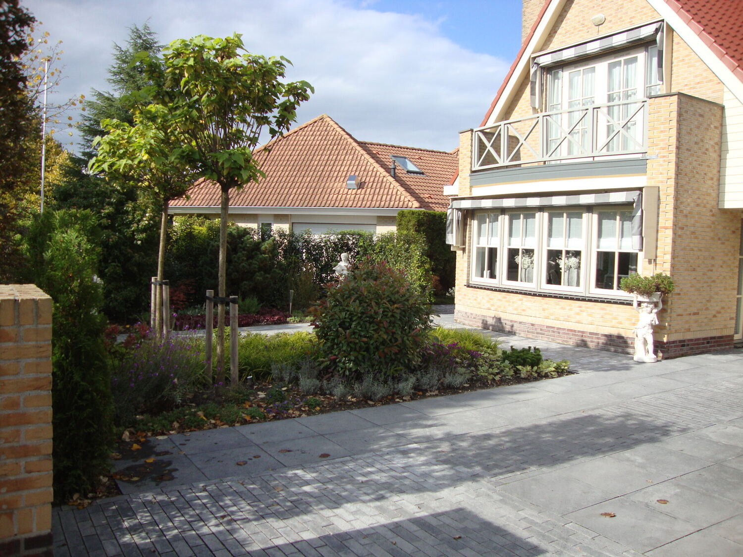 Particuliere tuin met tuinpad, borders en bomen
