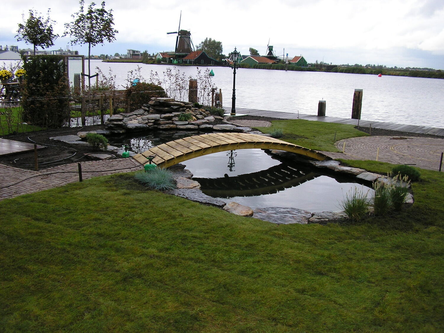 Tuin met vijver, bruggetje en zicht op de Zaan en molens